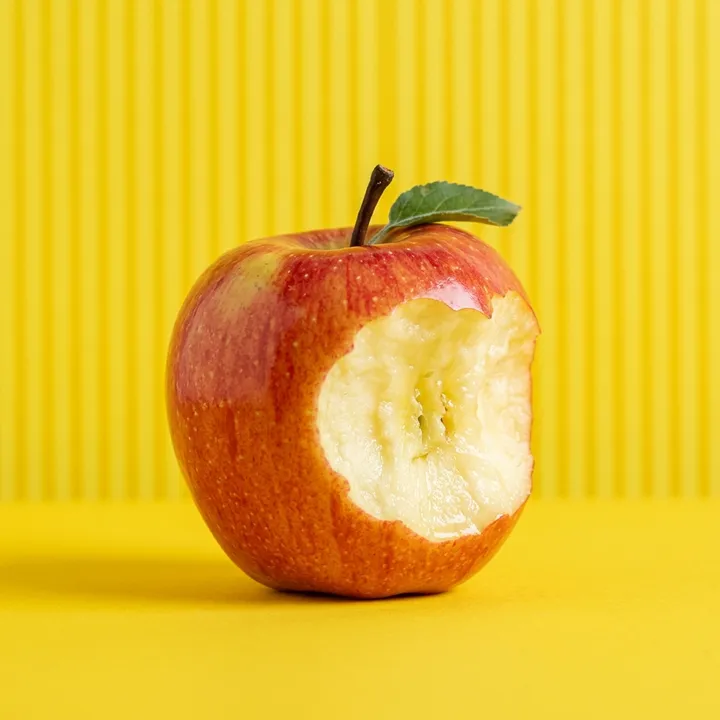 Apfel mit Biss vor gelbem Hintergrund